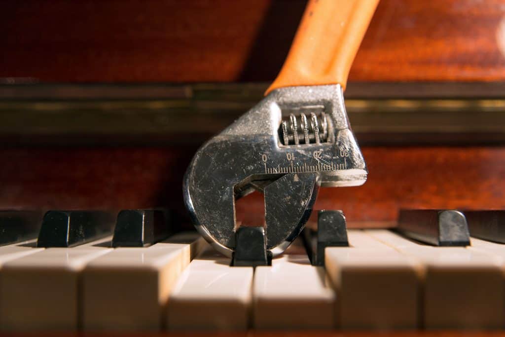 An adjustable wrench holding a piano key