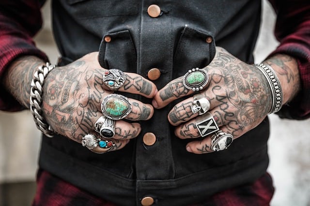 A person with tattoed hands and arms, and with rings and bracelets