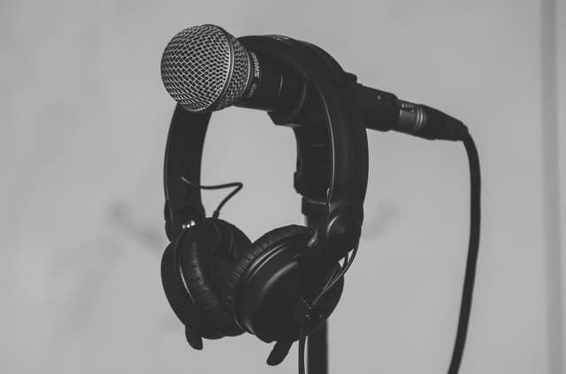 Black headphones hanging on a black and gray microphone